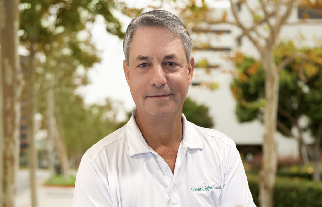 A headshot of John Simon with a nature background.