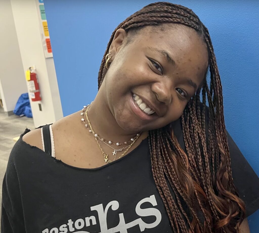 Ashley, the subject of this story, smiling wearing a Boston Arts Academy shirt.