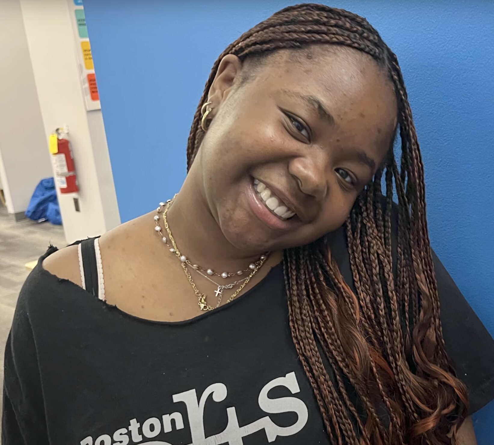 Ashley, the subject of this story, smiling wearing a Boston Arts Academy shirt.